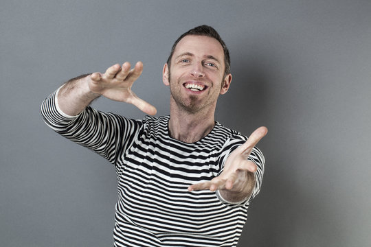 hand gesture concept - smiling energetic 40s man grabbing something or offering a generous hand forward,studio shot
