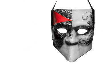Venetian style masquerade mask in black and white with a bit of red hanging in front of a white...