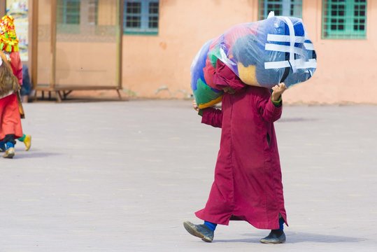 Man is carrying big bag with goods across the street in Marrakec