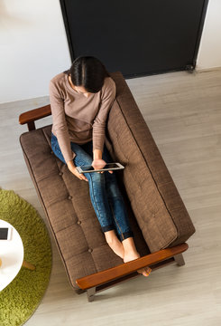Top view of woman use of the tablet pc and sitting on sofa