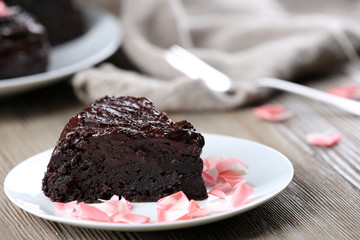 Piece of chocolate cake decorated with flowers on brown wooden table