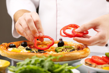 Cook making delicious pizza at the restaurant, close-up