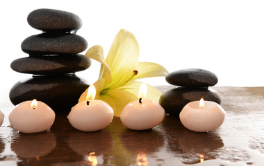 Fototapeta na wymiar Spa stones with candles and lily, isolated on white