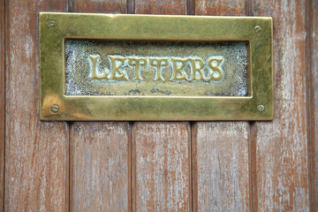 Brass letterbox in wooden door
