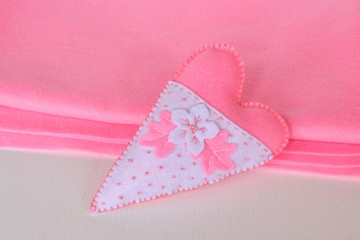 Hand-stitched felt heart - symbol of Valentines Day, on pink background, beautiful heart handmade