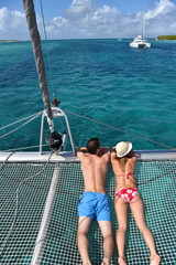 Couple suntanning on a catamaran net