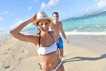 CHeerful couple running on sandy beach in Caribbean island