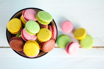 Sweet and colourful French macaroons in the dessert bowl on wooden table