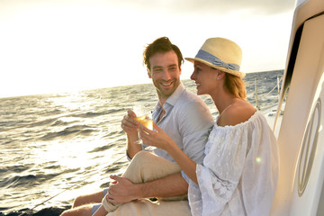 Romantic couple cheering on sailboat at sunset - Powered by Adobe