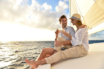 Romantic couple cheering on sailboat at sunset - Powered by Adobe