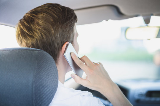Junger Mann sitzt im Auto und telefoniert