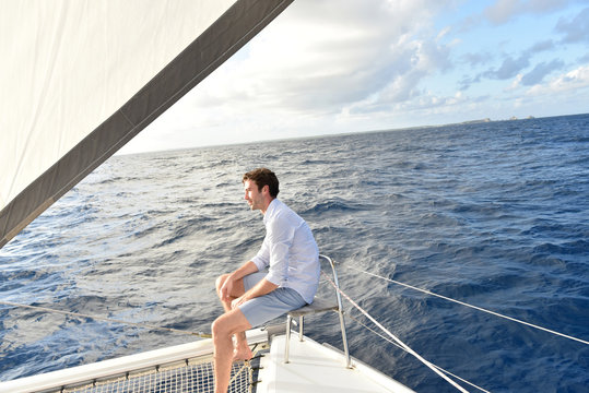 Handsome man relaxing on saiboat in middle of the sea