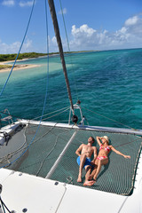 Couple suntanning on a catamaran net