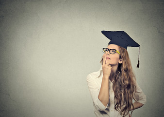 thoughtful graduate graduated student young woman in cap gown looking up thinking