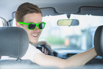 Naklejka premium Junger Mann mit Sonnenbrille sitzt im Auto