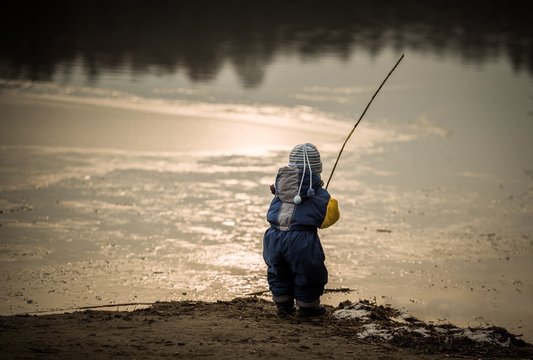 Little boy playing outdoor on frozen lake shore.