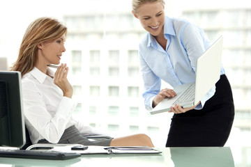 Obraz premium Look at this - Attractive businesswoman presenting project on laptop to female CEO