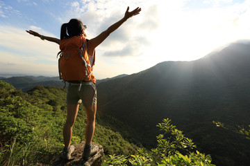 young woman hiker enjoy the beautiful landscape at mountain peak rock