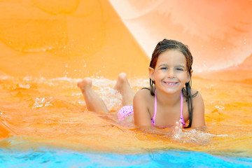 Adorable toddler girl on water slide at aquapark