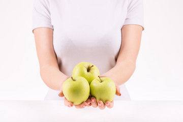 Woman demonstrating three green apples. 