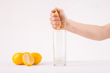 Female hand squeezing piece of orange to get juice.