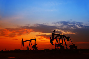 Fototapeta na wymiar Oil field scene, the evening of beam pumping unit in silhouette