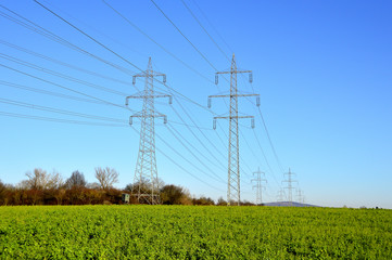 Freileitungsmasten auf gr&uuml;nem Feld