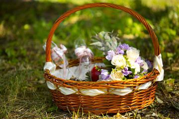 Fototapeta na wymiar Корзина для пикника с букетом невесты и бокалами на траве