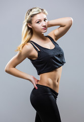 Attractive fit woman exercising in studio with copyspace. Image of healthy young female athlete doing fitness workout against grey background.