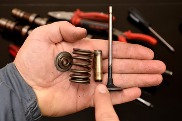 car mechanic shows valve assembly parts, valve, guide, spring, retainer