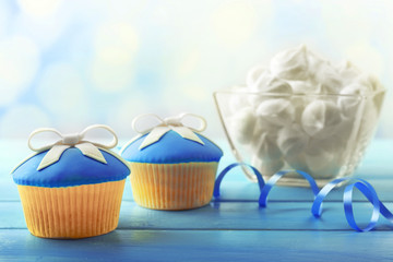 Tasty cupcake with bow on color wooden table, on bright background