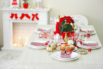 Christmas table setting with holiday decorations on fireplace background