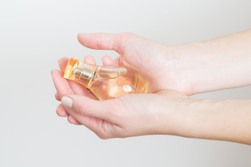 Womans hand holding a boutle with parfumes on white