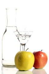 Bottle with transparent water, a glass and apples on a white background