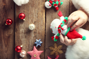 Christmas concept. Santa Claus makes toy, close up. Christmas decorations on wooden table.