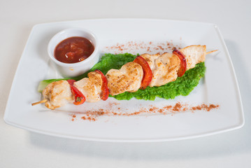 skewers with vegetables and tomato sauce on a plate in a restaurant