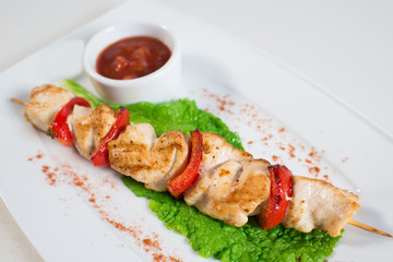 skewers with vegetables and tomato sauce on a plate in a restaurant