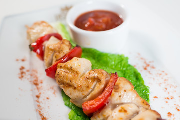 skewers with vegetables and tomato sauce on a plate in a restaurant