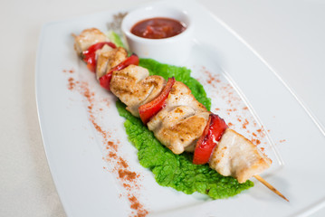 skewers with vegetables and tomato sauce on a plate in a restaurant