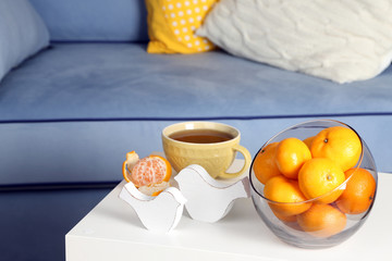 Bowl with fresh tangerines on table in living room, close up