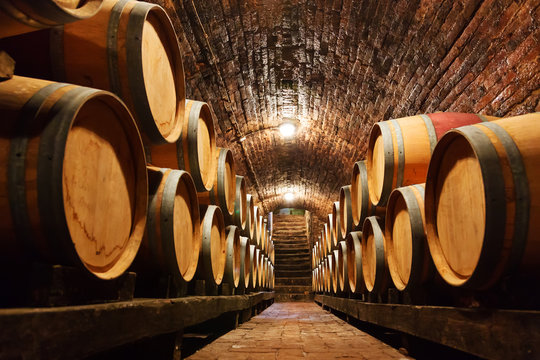 Naklejka Oak barrels in a underground wine cellar