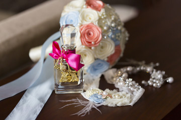 Fototapeta na wymiar Духи с розовым бантом и брелками, подвязка невесты, колье и букет невесты из тканевых цветов