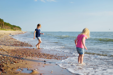 Two little sisters having fun on a sandy beach