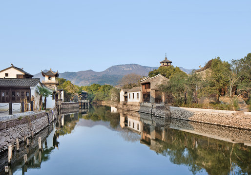 Ancient white Chinese houses reflected in a tranquil canal, Hengdian, China
