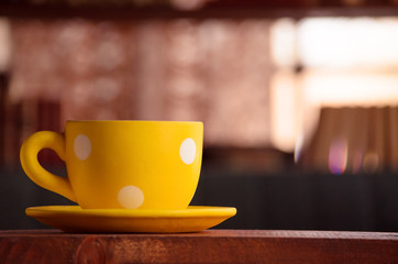 Fototapeta premium Dotted yellow cup on the table 