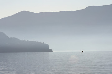 Kayak crossing lake in the mountains on a misty morning