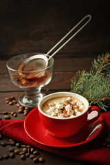 Mug of hot chocolate with marshmallows, fir tree branch on wooden background