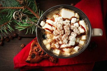 Mug of hot chocolate with marshmallows, fir tree branch on wooden background