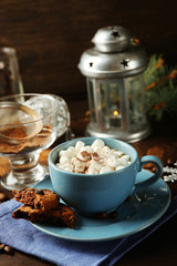 Mug of hot chocolate with marshmallows, fir tree branch on wooden background