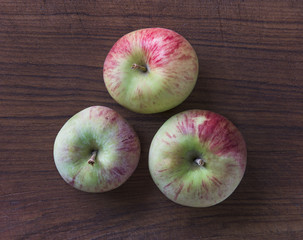 Heirloom Red Delcious Hybrid Apples with mottled yellow-green and red coloration on an old wooden cutting board